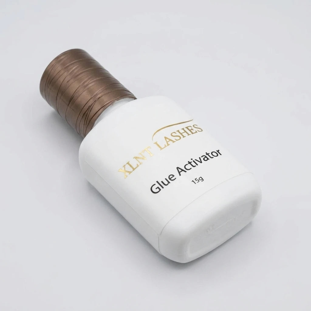 XLNT Lashes 15g Glue Activator bottle, eyelash extension adhesive booster with a textured bronze cap.