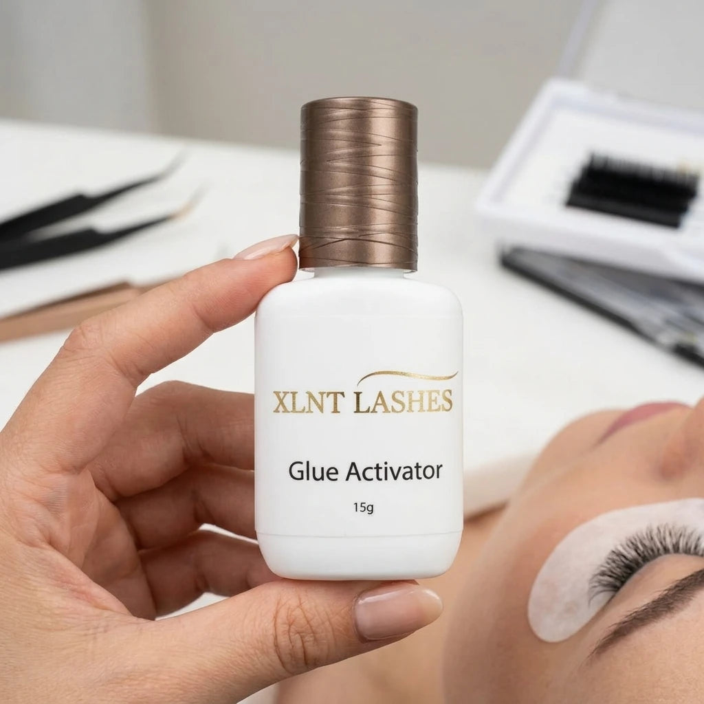 XLNT Lashes Glue Activator 15g bottle held by a lash tech during an eyelash extension application.
