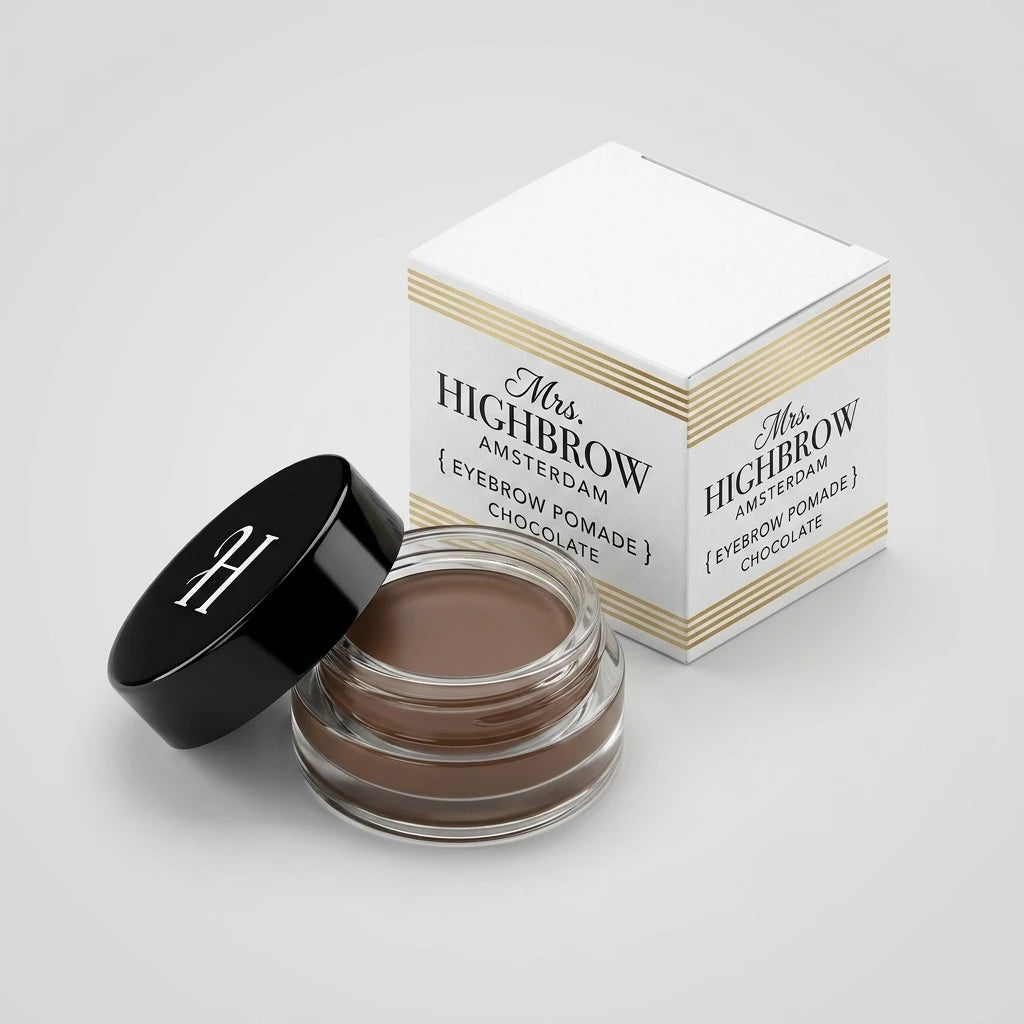 Mrs. Highbrow Eyebrow Pomade i öppen glasburk med svart lock och guldfärgad produktförpackning på grå bakgrund.