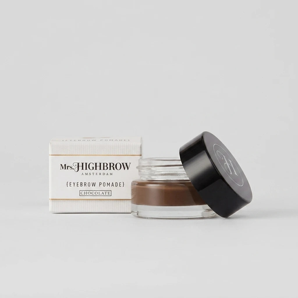 Mrs. Highbrow Eyebrow Pomade Chocolate i glasburk med svart lock bredvid vit förpackning på ljus bakgrund.