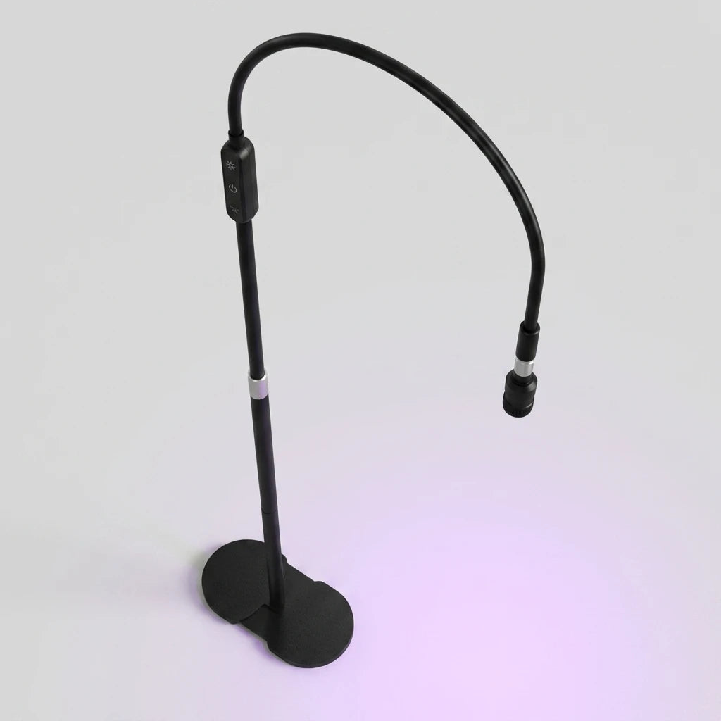 Svart UV-Led Lampa Fransar Deluxe med böjbar arm och stabil fot som sprider ett lila sken på ljus bakgrund.