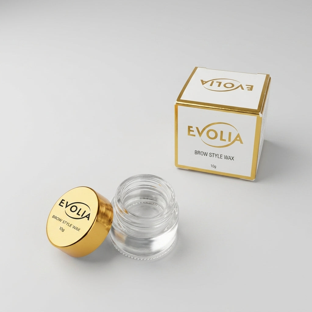 Evolia Brow Wax i öppen glasburk med guldlock bredvid vit och guldfärgad förpackning på ljus bakgrund.