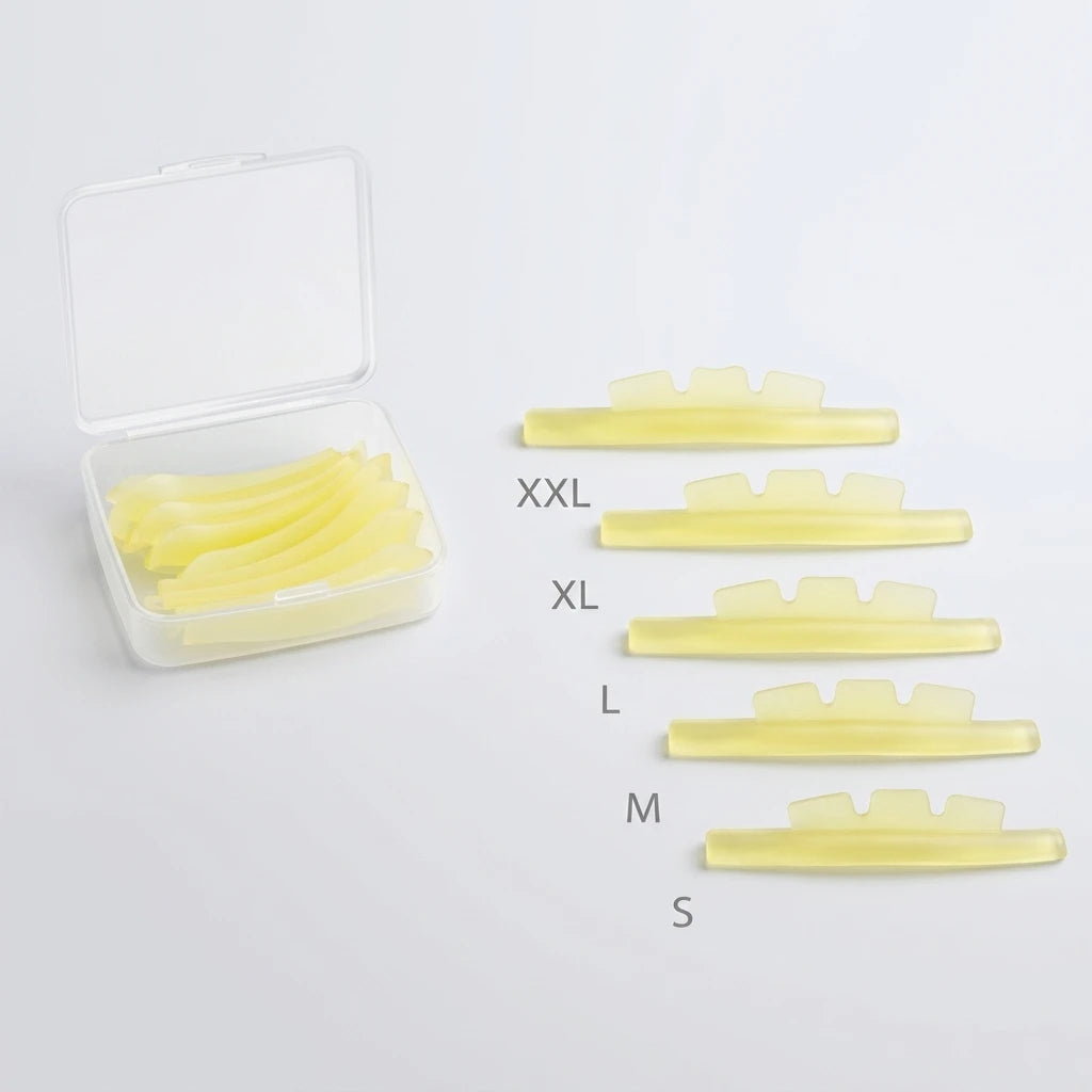 Gula kronformade silikonspolar för Korean Lash lift spole Crown i storlek S-XXL bredvid en transparent plastask.