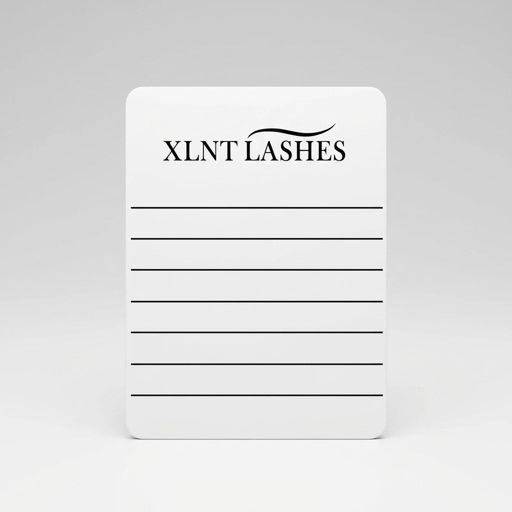 Rektangulär vit fransplatta för handen med svarta linjer och XLNT Lashes logotyp mot ljusgrå bakgrund.