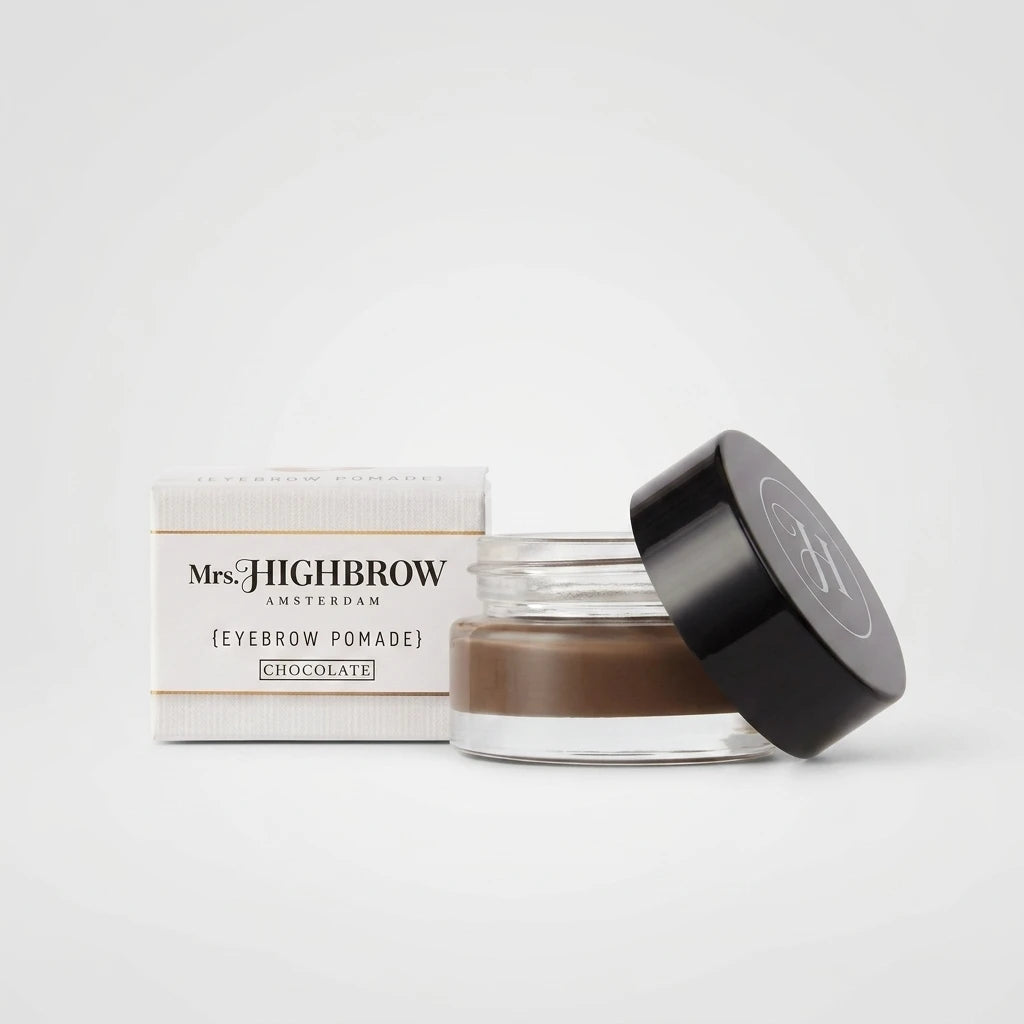 Mrs. Highbrow Eyebrow Pomade i nyansen Chocolate – öppen glasburk med svart lock bredvid förpackningen.