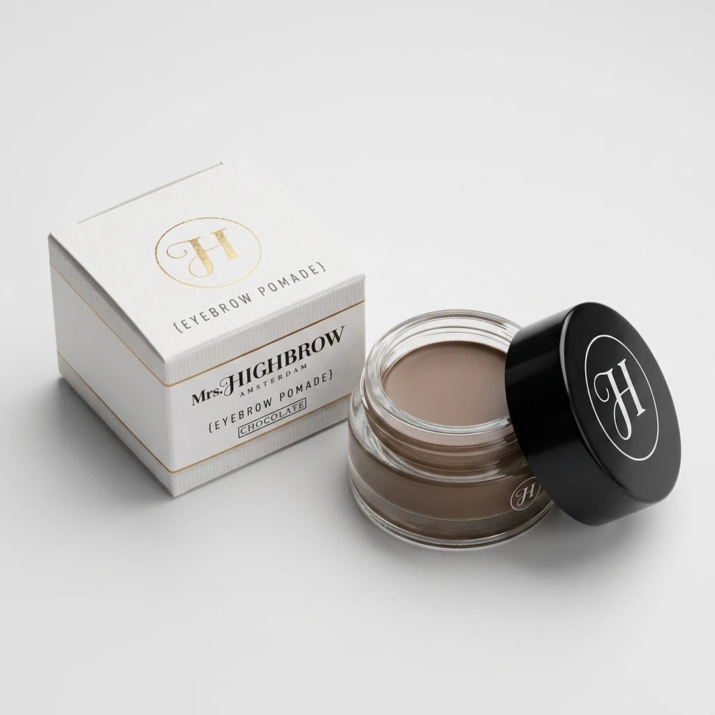 Mrs. Highbrow Eyebrow Pomade Chocolate uppifrån höger – öppen glasburk bredvid vit pappersförpackning.