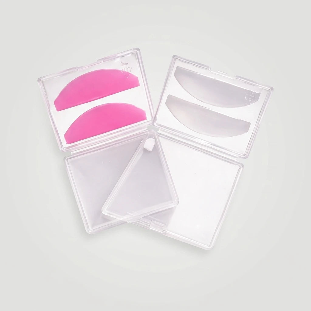 Rosa och genomskinliga Korean Lash lift spole Flat silikonspolar i öppna plastetuier på ljusgrå bakgrund.