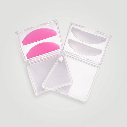 Rosa och genomskinliga Korean Lash lift spole Flat silikonspolar i öppna plastetuier på ljusgrå bakgrund.