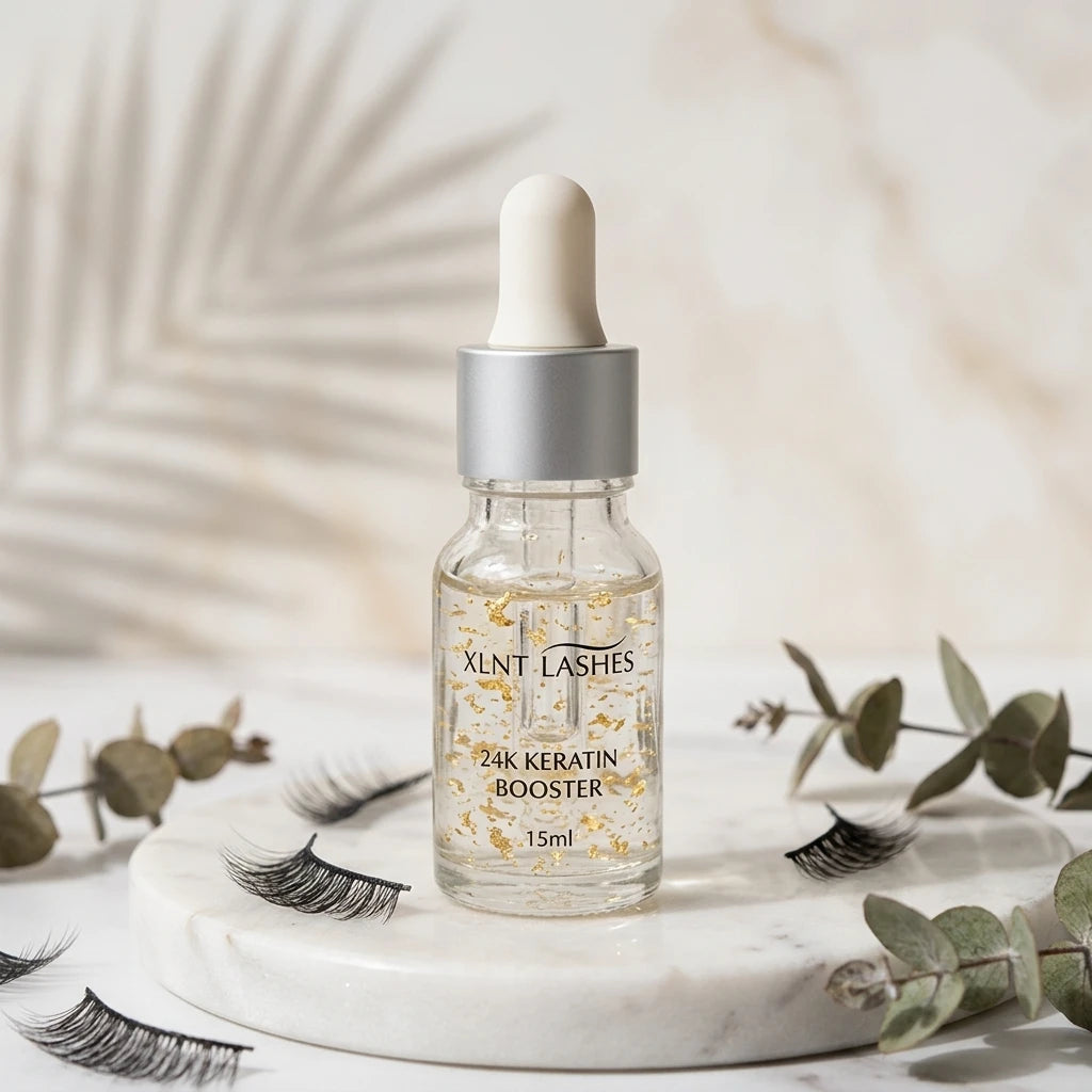 Lash & Brow Lift No.3 24k Essence i pipettflaska med guldflagor på vit marmorplatta bredvid lösfransar.