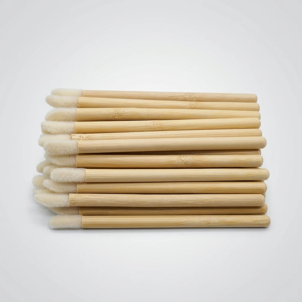 Applikatorborste 50st Bambu staplade horisontellt med ljusa mjuka tippar och träskaft mot ljusgrå bakgrund.