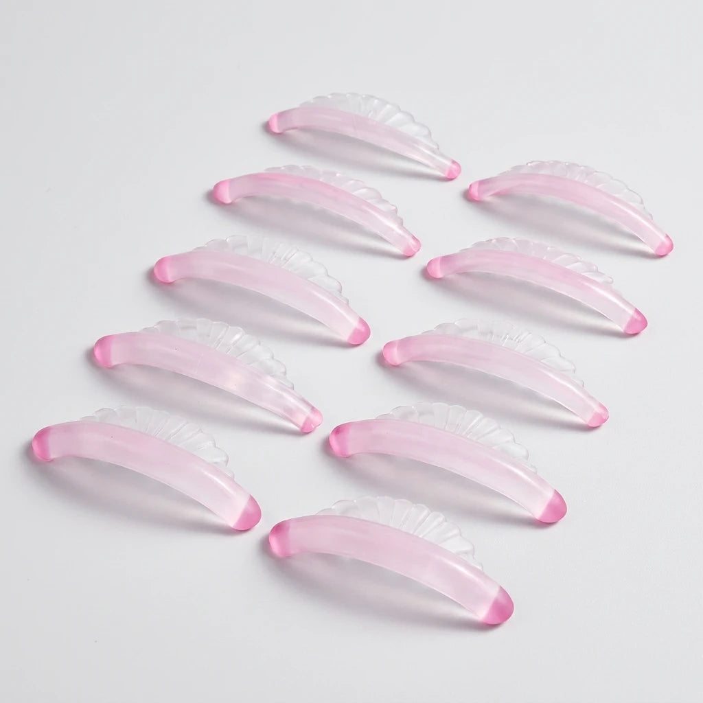 Rosa, snäckformade och halvtransparenta Korean Lash lift spole Shell i mjukt silikon på ljus bakgrund.