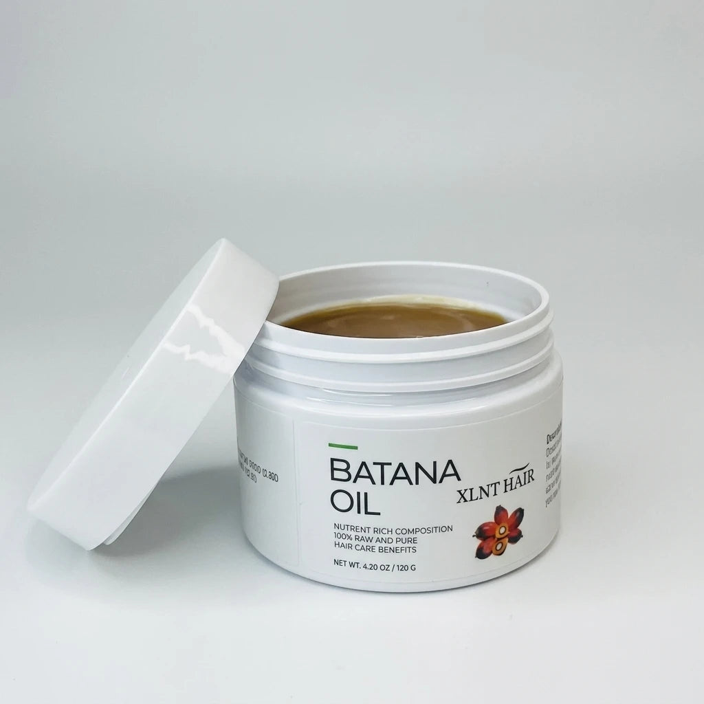 Öppen vit burk med mörkbrun Batana Oil 120g och ett vitt lock lutat mot sidan på en vit bakgrund.