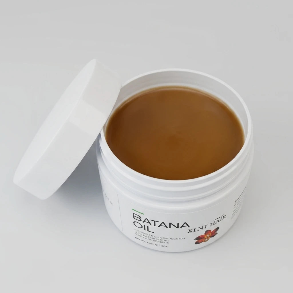 Öppen vit burk med brun Batana Oil 120g hårolja och ett vitt lock lutat mot sidan på ljusgrå bakgrund.