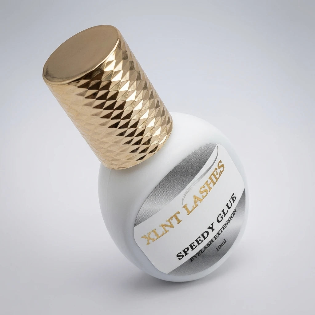 Vinklad vit flaska med mönstrat guldlock för XLNT Lashes Speedy Glue 10ml 1-3 Sek franslim mot ljus bakgrund.