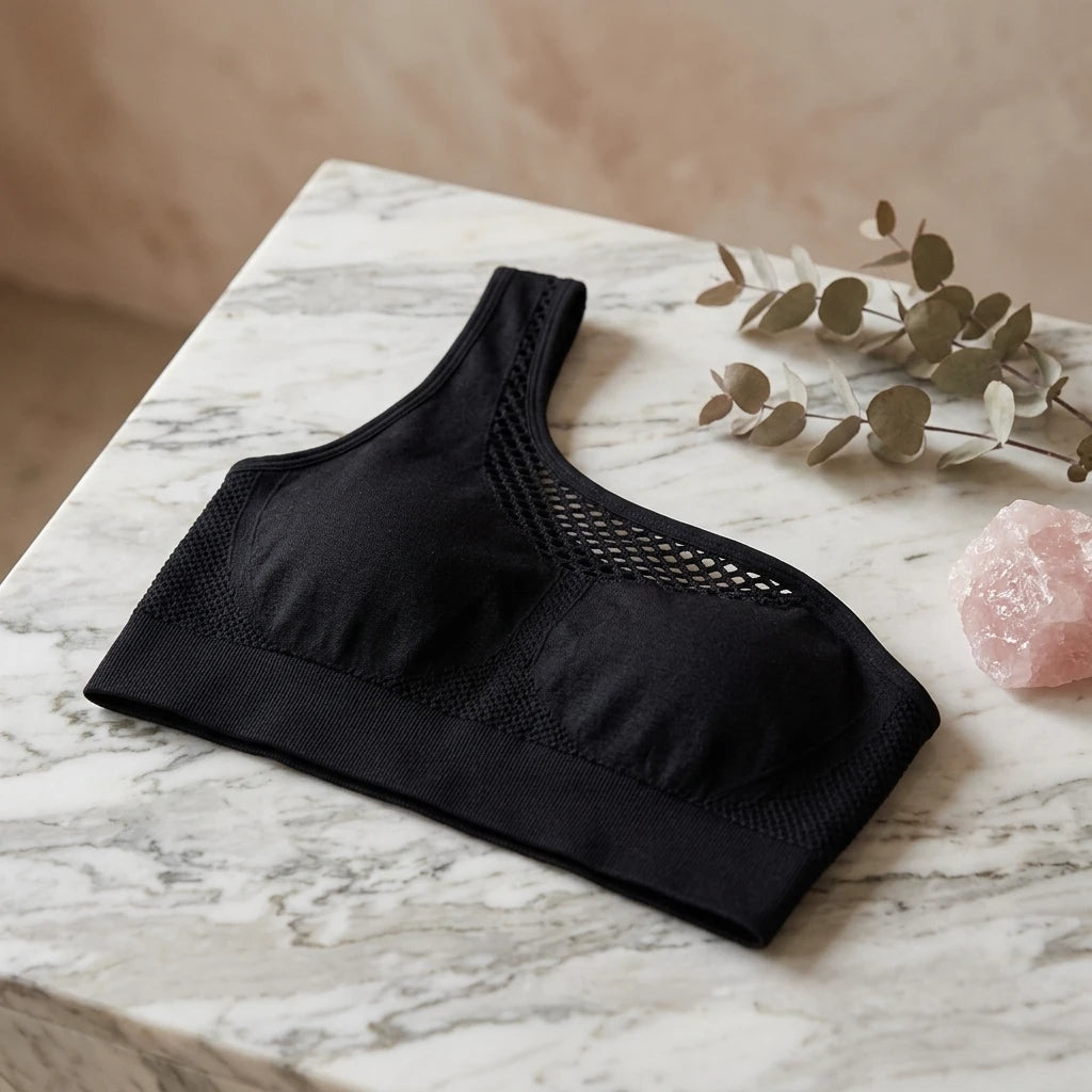 Svart seamless sport-bh med meshdetaljer placerad på marmorskiva bredvid rosa kristall, miljöbild.