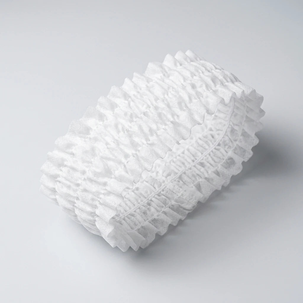 Rynkat vitt engångshårband i nonwoven-material mot ljusgrå bakgrund, sett från höger