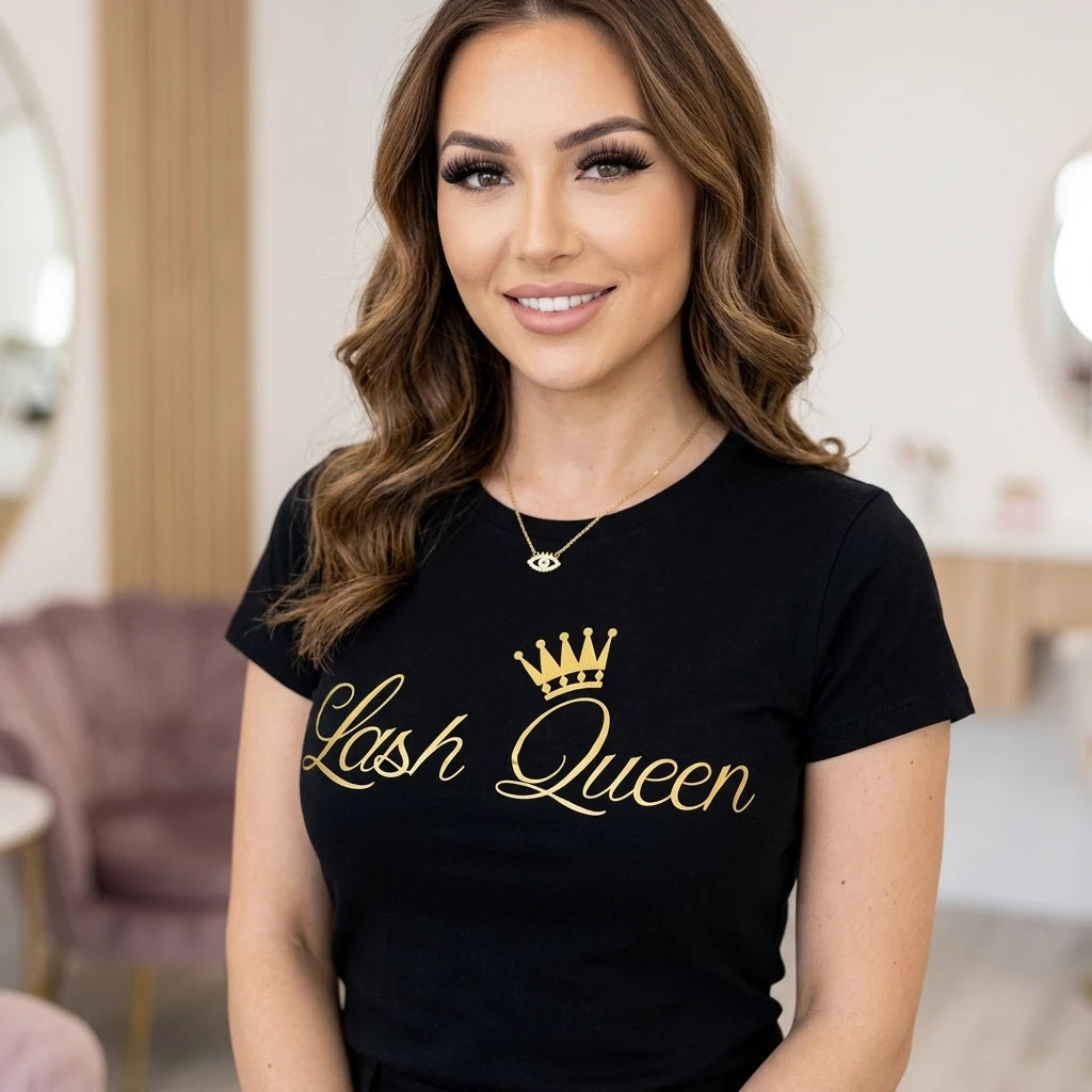 Leende lashstylist bär svart Lash Queen T-Shirt med guldtryck och krona, naturlig salong miljö.