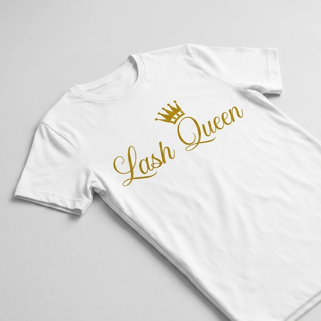 Lash Queen T-shirt i vitt bomullsmaterial med guldglänsande tryck och krona, fotograferad ovanifrån på ljusgrå yta.