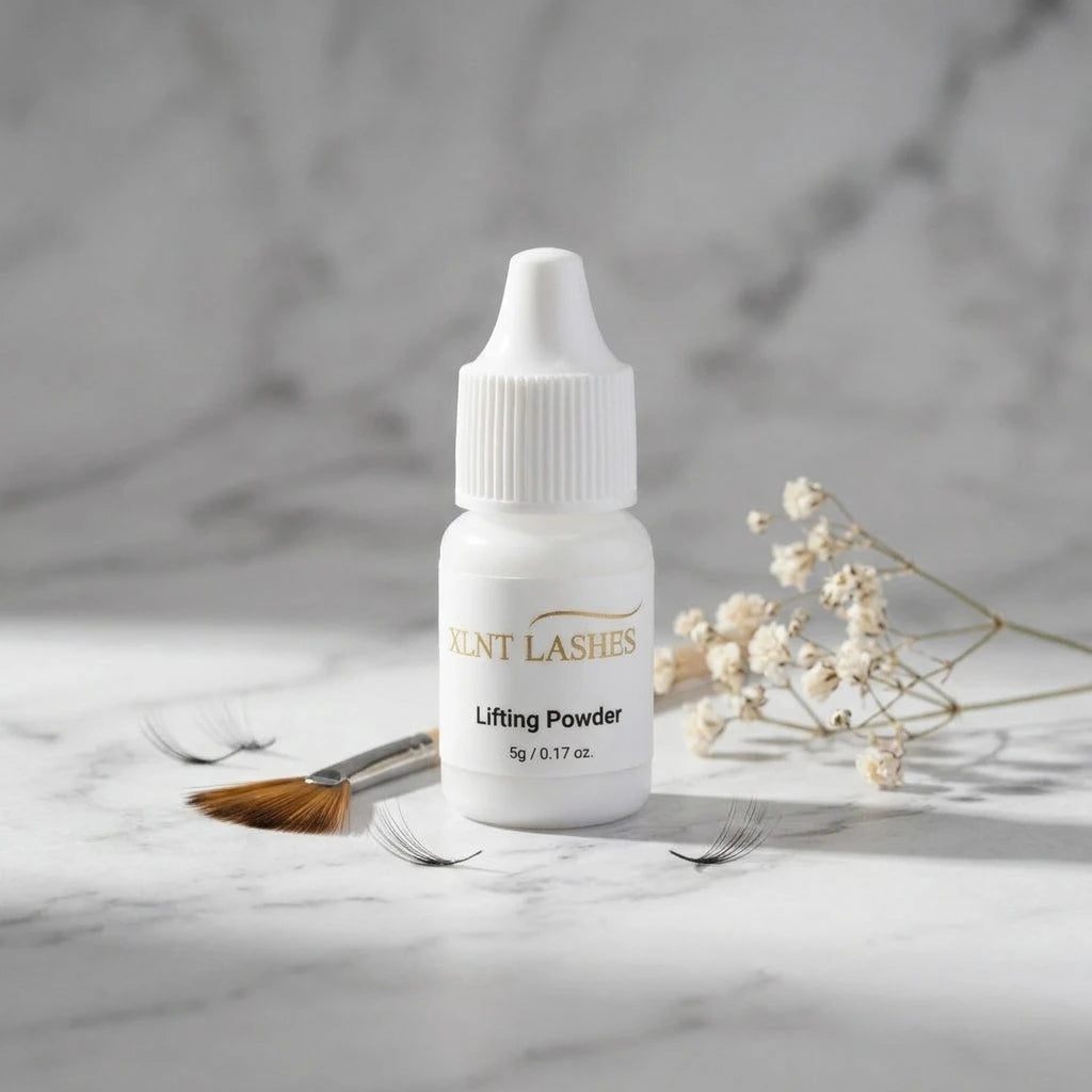 Lifting Powder 5g på marmoryta omgiven av lösfransar, pensel och torkade blommor – miljöbild.