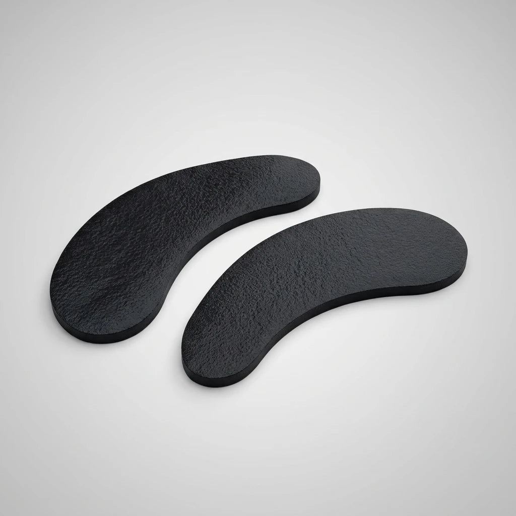 Två svarta, böjda och texturerade ögonkuddar från Lint Free Eyepads Svarta 50pack mot en ljusgrå bakgrund.