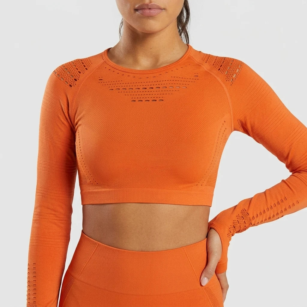 Orange seamless mesh crop top med långa ärmar, framsida mot ljusgrå bakgrund.