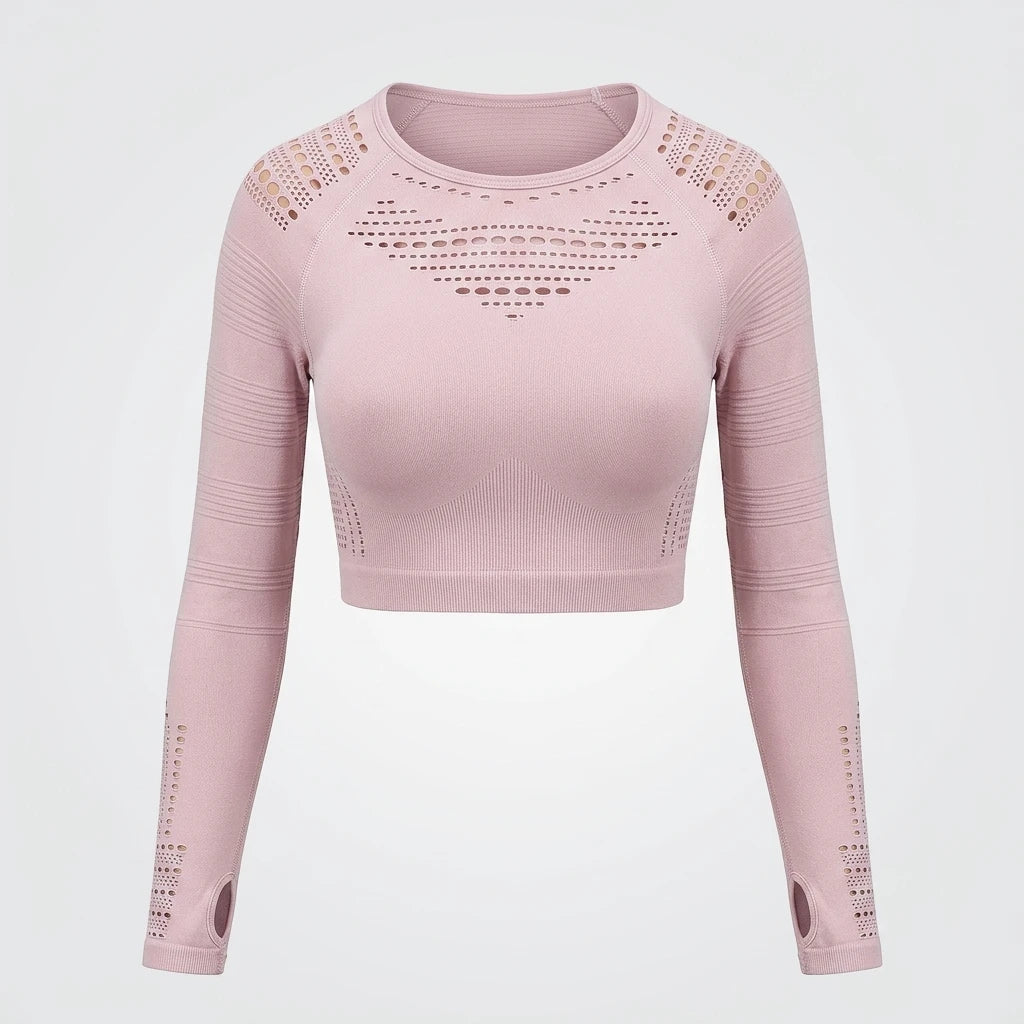Sömlös puderrosa mesh crop top med hålmönster, tumhål och långärmad design mot ljus bakgrund.