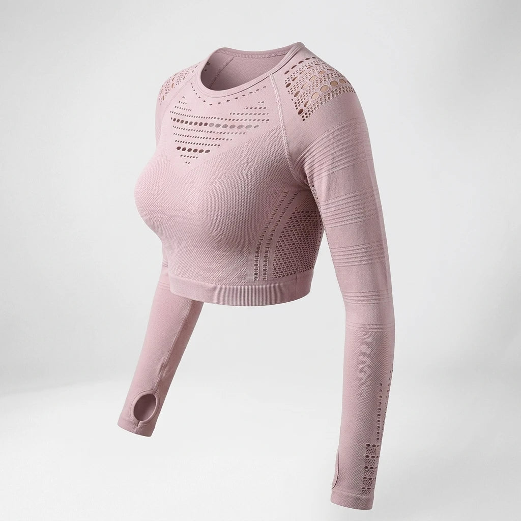 Närbild på puderrosa seamless crop top med stickat hålmönster och tumhål mot ljus bakgrund.