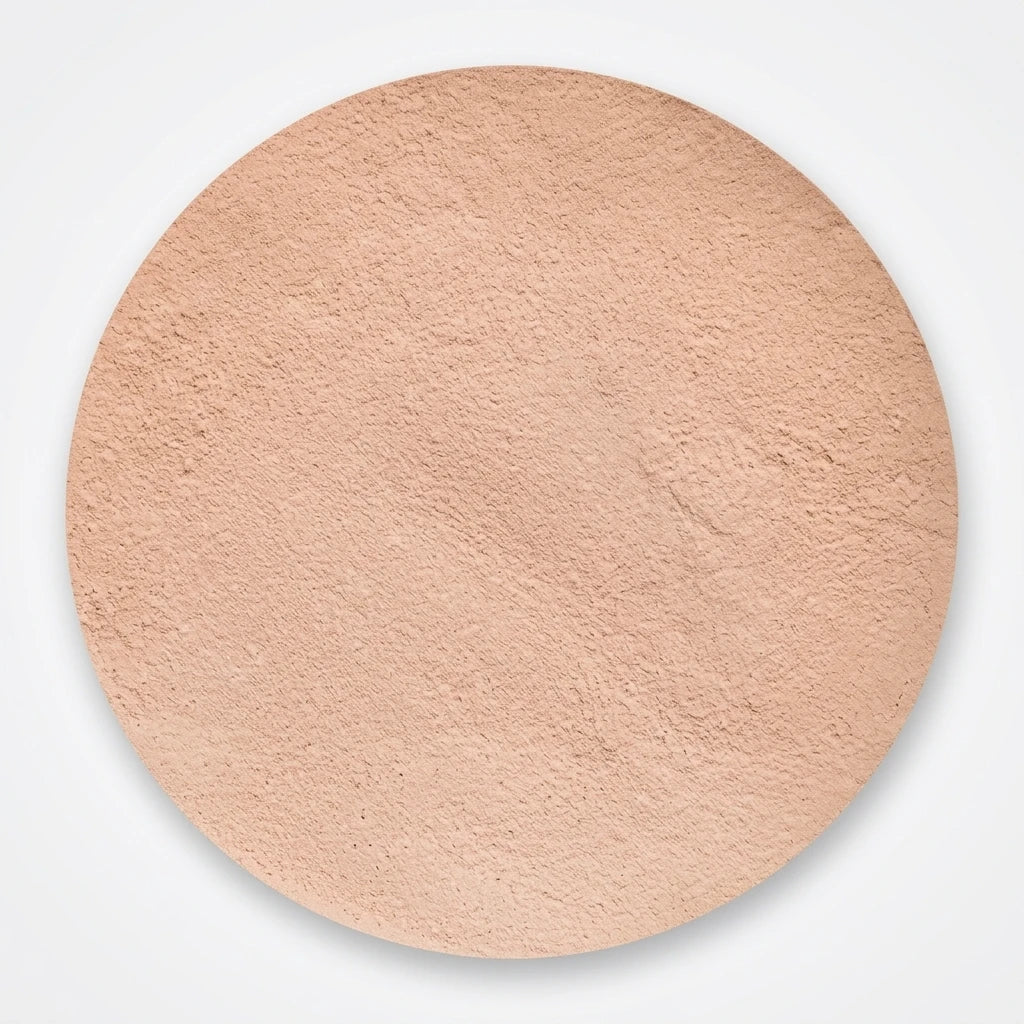 Cirkelformat färgprov av beige finkornigt Moyana Corigan Mineral Puder mot vit bakgrund.