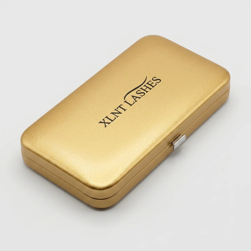Rektangulärt Pincett Fodral Guld med svart XLNT LASHES-logotyp och silvrigt knäppe på ljusgrå bakgrund.