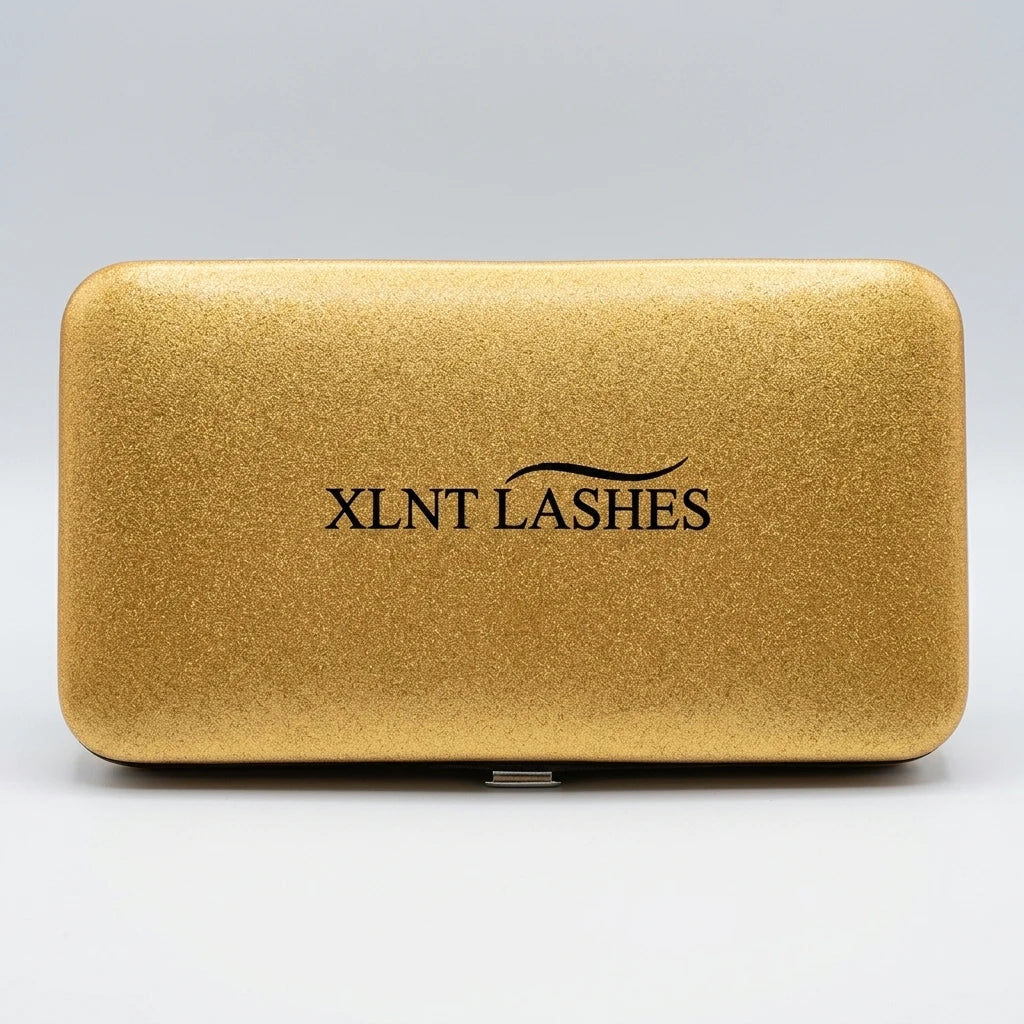 Glittrigt, rektangulärt Pincett Fodral Guld med XLNT Lashes logotyp centrerad mot ljus bakgrund.