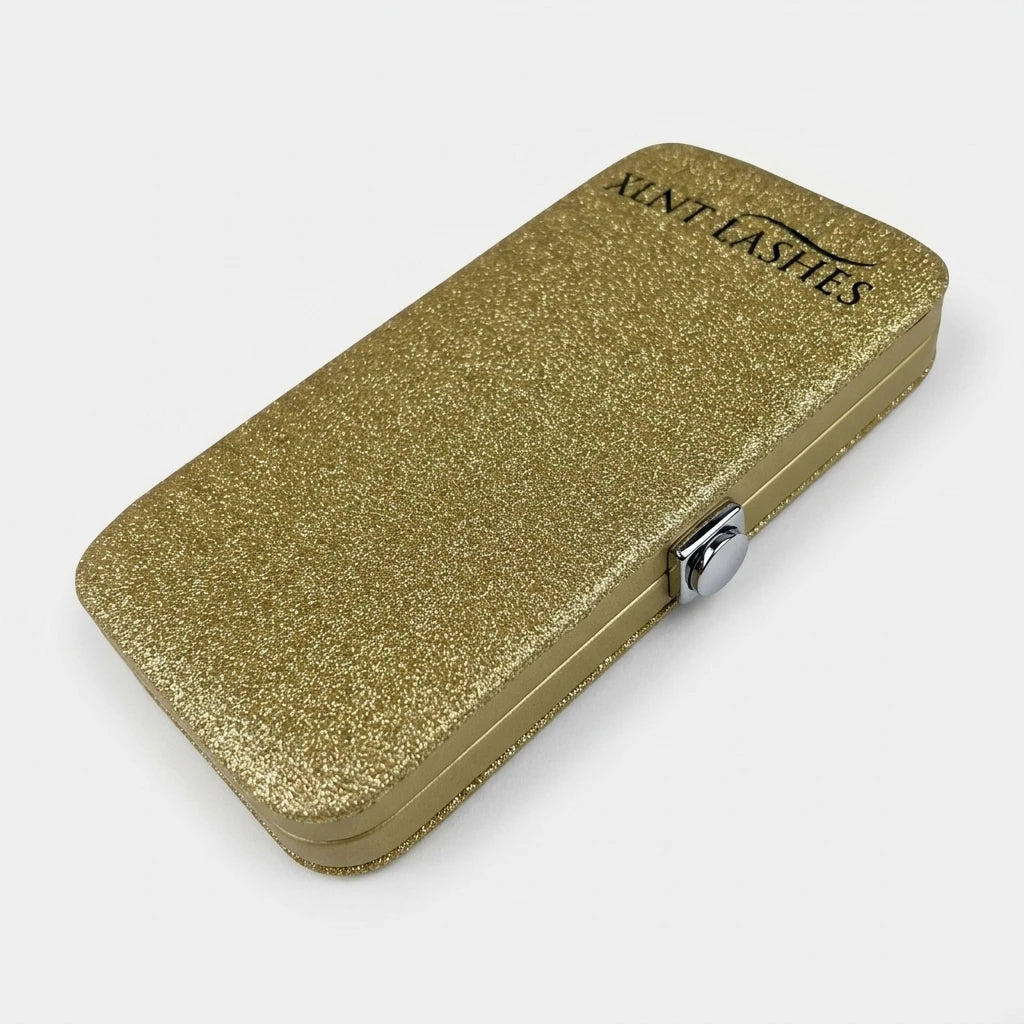 Rektangulärt Pincett Fodral Guld glitter med XLNT LASHES-logotyp och silverknapp på vit bakgrund.