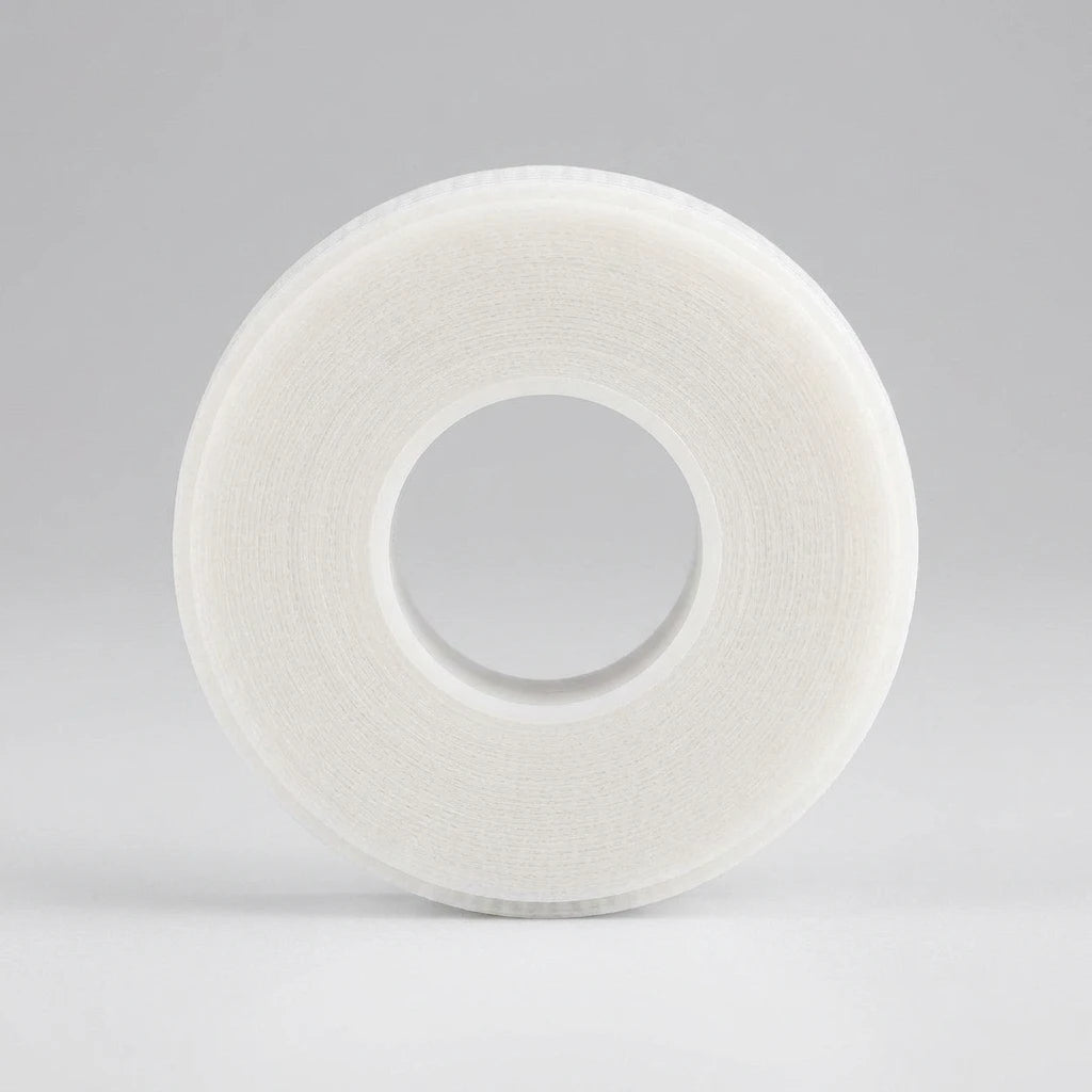 Rund rulle av Silikontejp Vit 1,25cm i halvtransparent material mot en ljusgrå bakgrund.