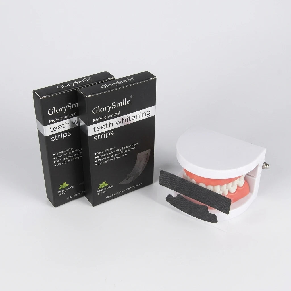 GlorySmile tandblekningsremsor 28-pack med PAP och aktivt kol i svart förpackning bredvid en vit tandmodell