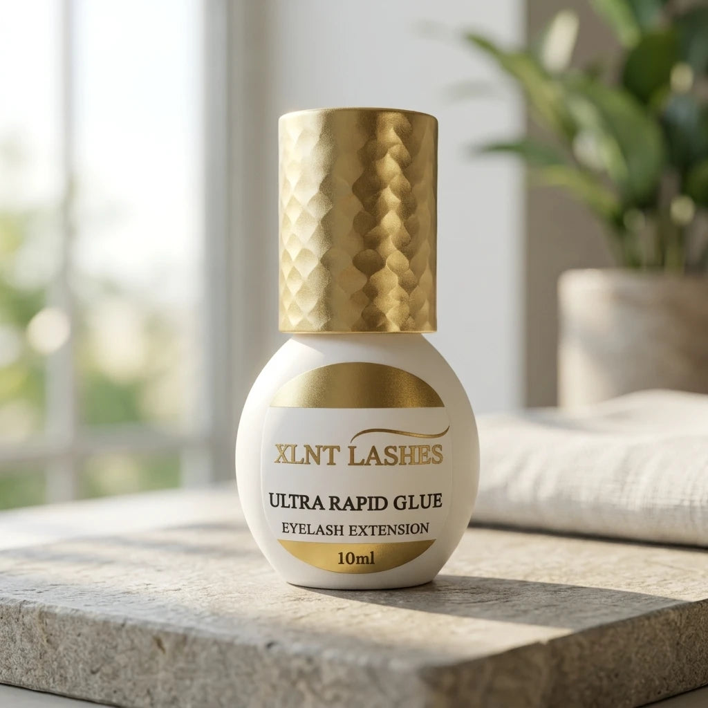 Ultra Rapid Glue 10ml svart fransförlängningslim i vit flaska med guldkork på naturlig stenskiva.